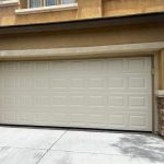Closed beige garage door on a modern house with stone accents and the street number 10172 visible.
